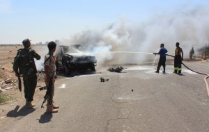 Yemeni security forces extinguish fire at a site where a bomb-laden car exploded in Aden's Mansura district on May 1, 2016. A bomb-laden car exploded as General Shallal Shayae's convoy passed, damaging military vehicles and prompting clashes between his guards and Al-Qaeda suspects in the area, officials said, adding that four Yemeni guards were killed in the bombing that targeted the convoy of Aden's police chief, the second such attack on him this week. / AFP PHOTO / SALEH AL-OBEIDI