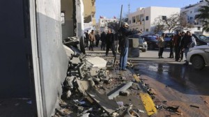 Civilians and security personnel stand at the scene of an explosion at a police station in the Libyan capital Tripoli March 12, 2015. Militants claiming loyalty to Islamic State said they were responsible for a bomb attack on a police station in the Libyan capital on Thursday, a statement posted on Twitter said. The militants published pictures of the blast at the police station, close to the Foreign Ministry in central Tripoli. A blast damaged the police station and cars outside, witnesses said. REUTERS/Hani Amara (LIBYA - Tags: POLITICS CIVIL UNREST CRIME LAW)