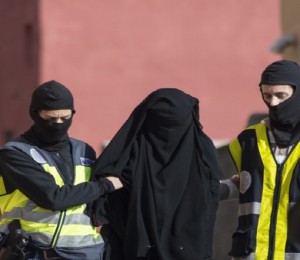 Spanish police escort a 20 year old Abaya clad woman in Melilla on December 16, 2014 during the combined arrests of seven people in Spain and Morocco for allegedly recruiting young women via the Internet to join the jihadist Islamic State group fighting in Iraq and Syria. The group had so far managed to recruit 12 women, mainly from Ceuta and Melilla, targeting young women with poor job prospects who used social networking sites without much supervision.  AFP PHOTO / JESUS BLASCO DE AVELLANEDA